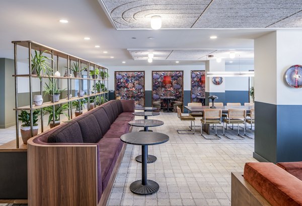 Modern lounge area with seating, tables, and decorative plants at The Lucie luxury apartments