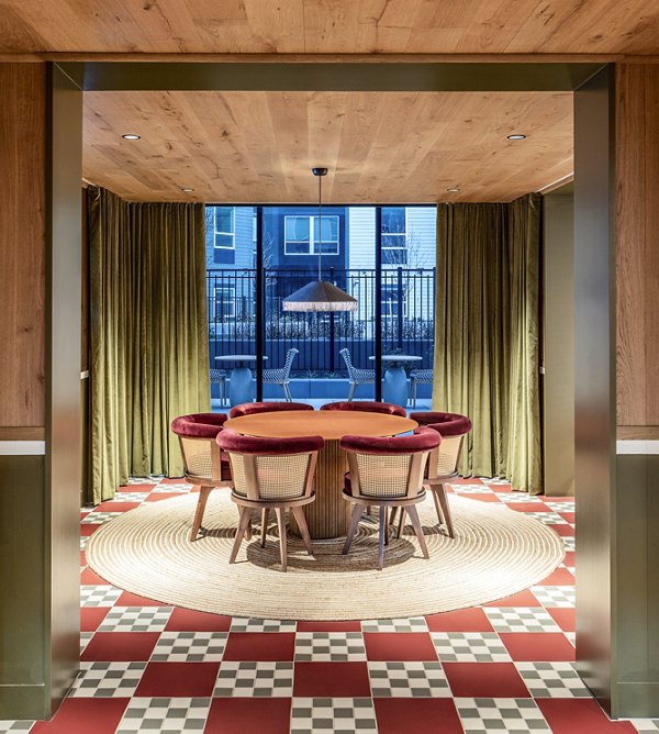 Dining area with round table, six chairs, and checkered floor tiles at The Lucie Apartments