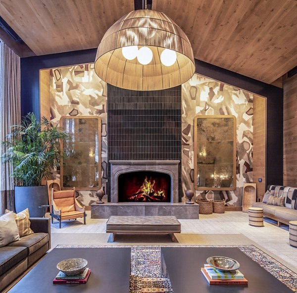 Spacious living room with fireplace, elegant chandelier, and plush seating in The Lucie Apartments