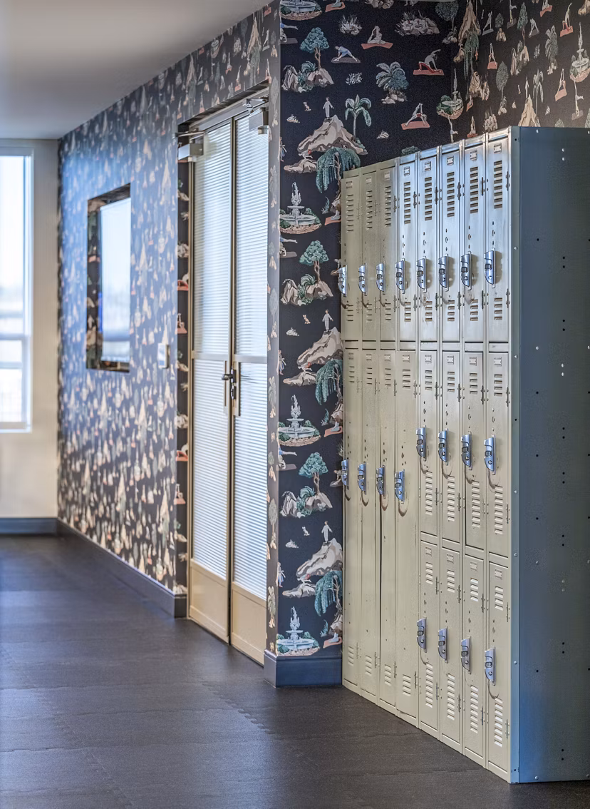 Hallway featuring lockers and patterned wallpaper at The Lucie Apartments