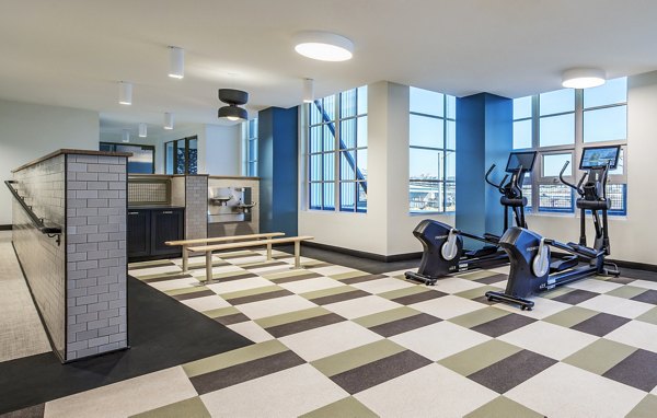 Bright fitness center with exercise bikes, checkered floor, and large windows at The Lucie Apartments luxury community