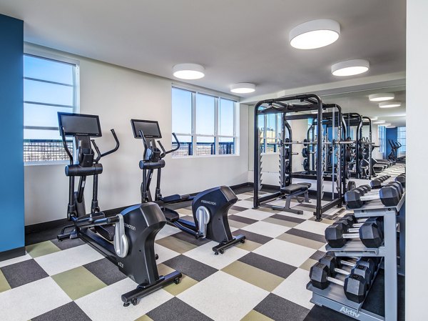 Bright and modern gym with exercise machines, weights, and large windows at The Lucie Apartments in vibrant downtown location