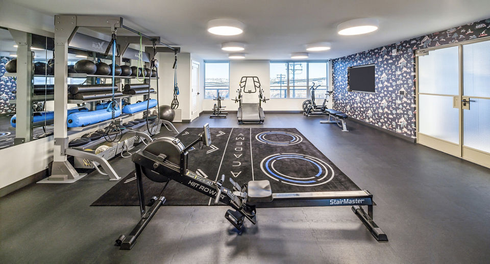 Modern fitness center with diverse exercise machines and free weights at The Lucie Apartments for active living