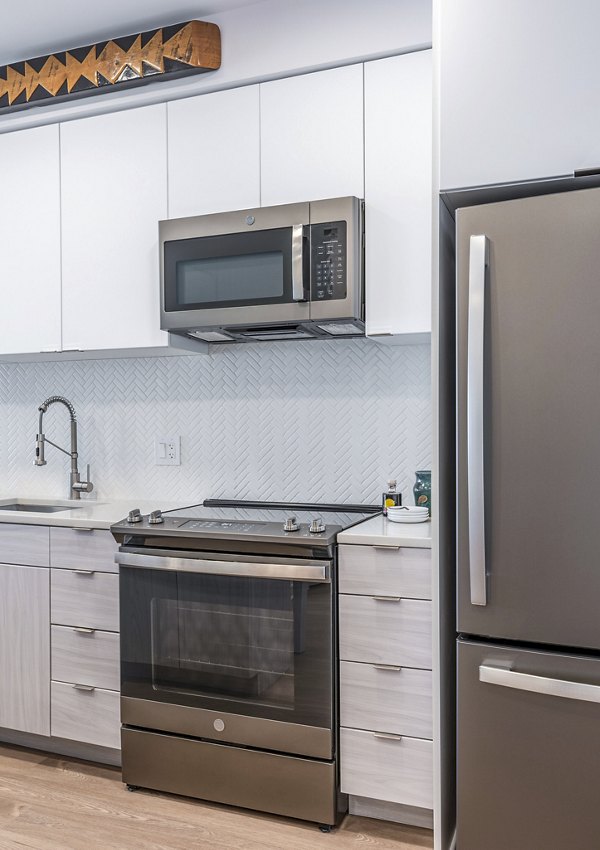 Sleek kitchen featuring stainless steel appliances and white cabinets at The Lucie Apartments