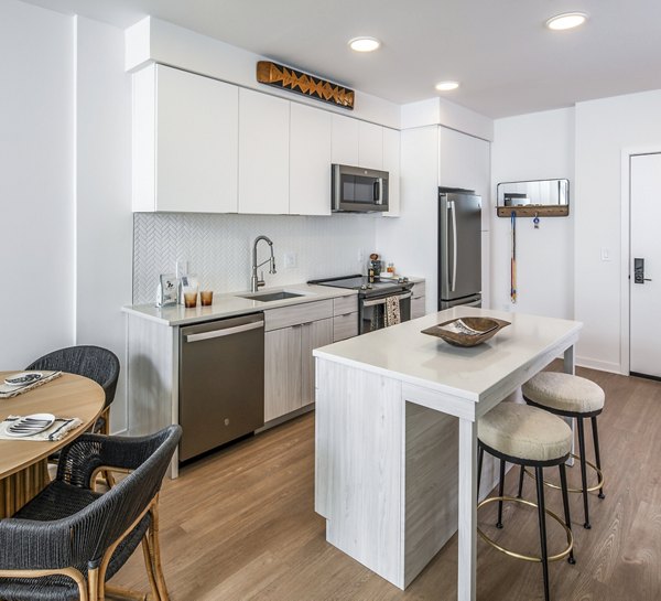 Sleek kitchen with island, dining table, and stainless steel appliances in The Lucie Apartments' luxury units