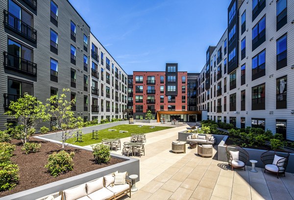 The Lucie Apartments: Inviting courtyard with seating and lush greenery surrounded by multi-story buildings in the heart of the community