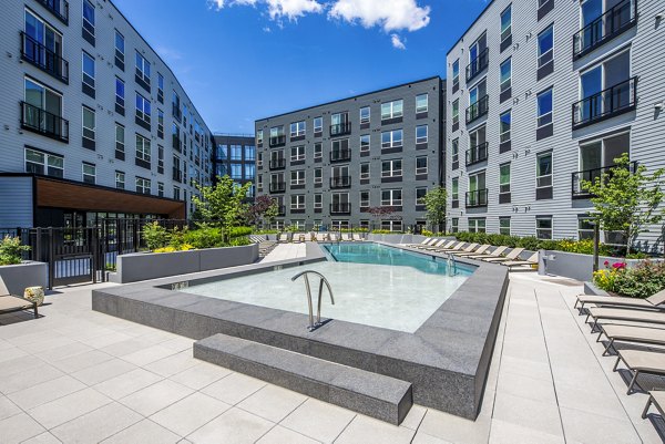 Courtyard with a pool, lounge chairs, and lush greenery at The Lucie Apartments, a luxury living community offering upscale amenities