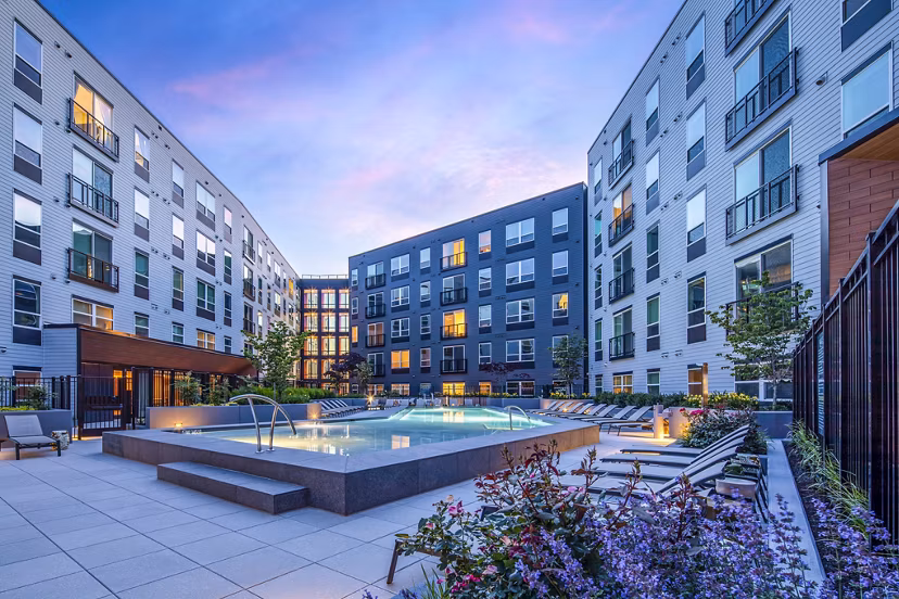 The Lucie Apartments: Luxury complex with pool and lounge chairs under an evening sky