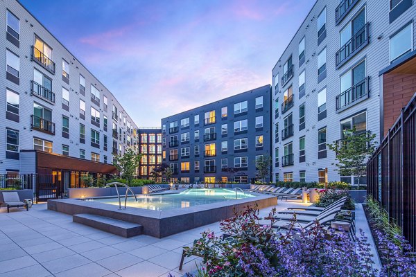 The Lucie Apartments: Luxury complex with pool and lounge chairs under an evening sky