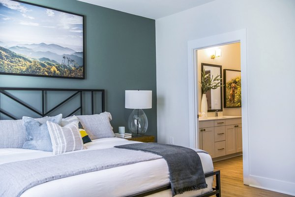 Luxurious bedroom with modern design at Novel Cary Apartments, featuring plush bedding and large windows for ample natural light