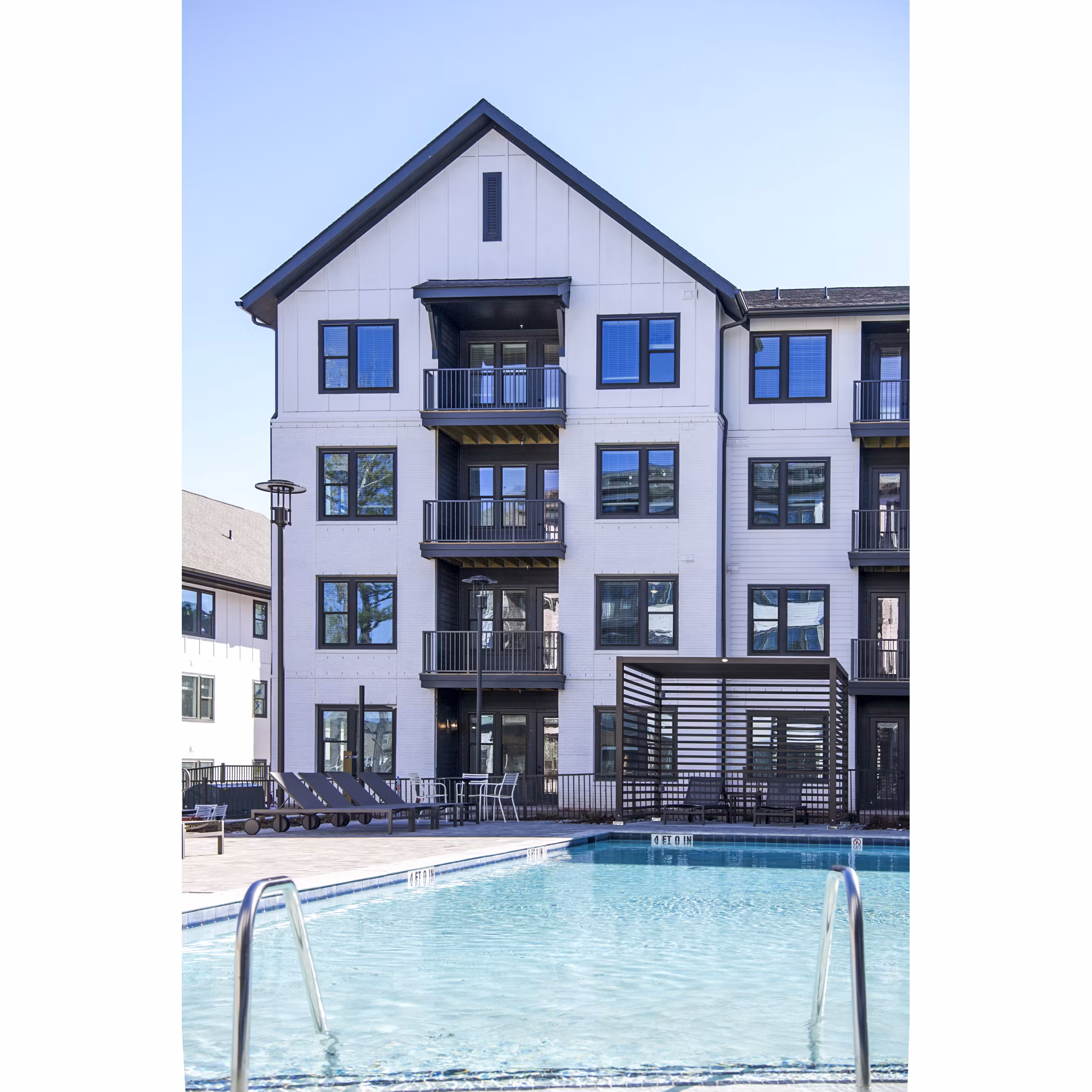 Modern, resort-style pool at Novel Cary Apartments featuring sun loungers and lush landscaping