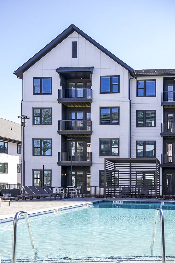 Modern, resort-style pool at Novel Cary Apartments featuring sun loungers and lush landscaping