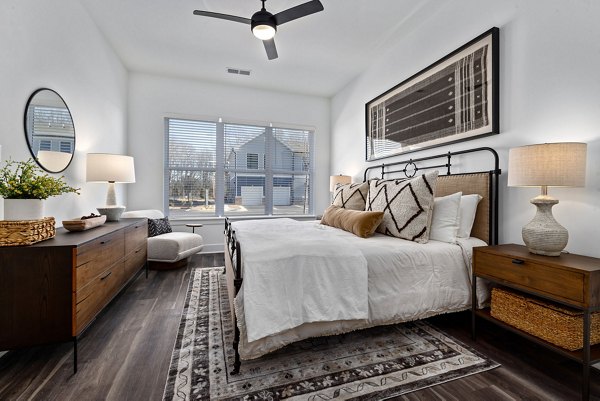 Cozy bedroom featuring modern decor and large windows in The Pace at Holding Village Apartments