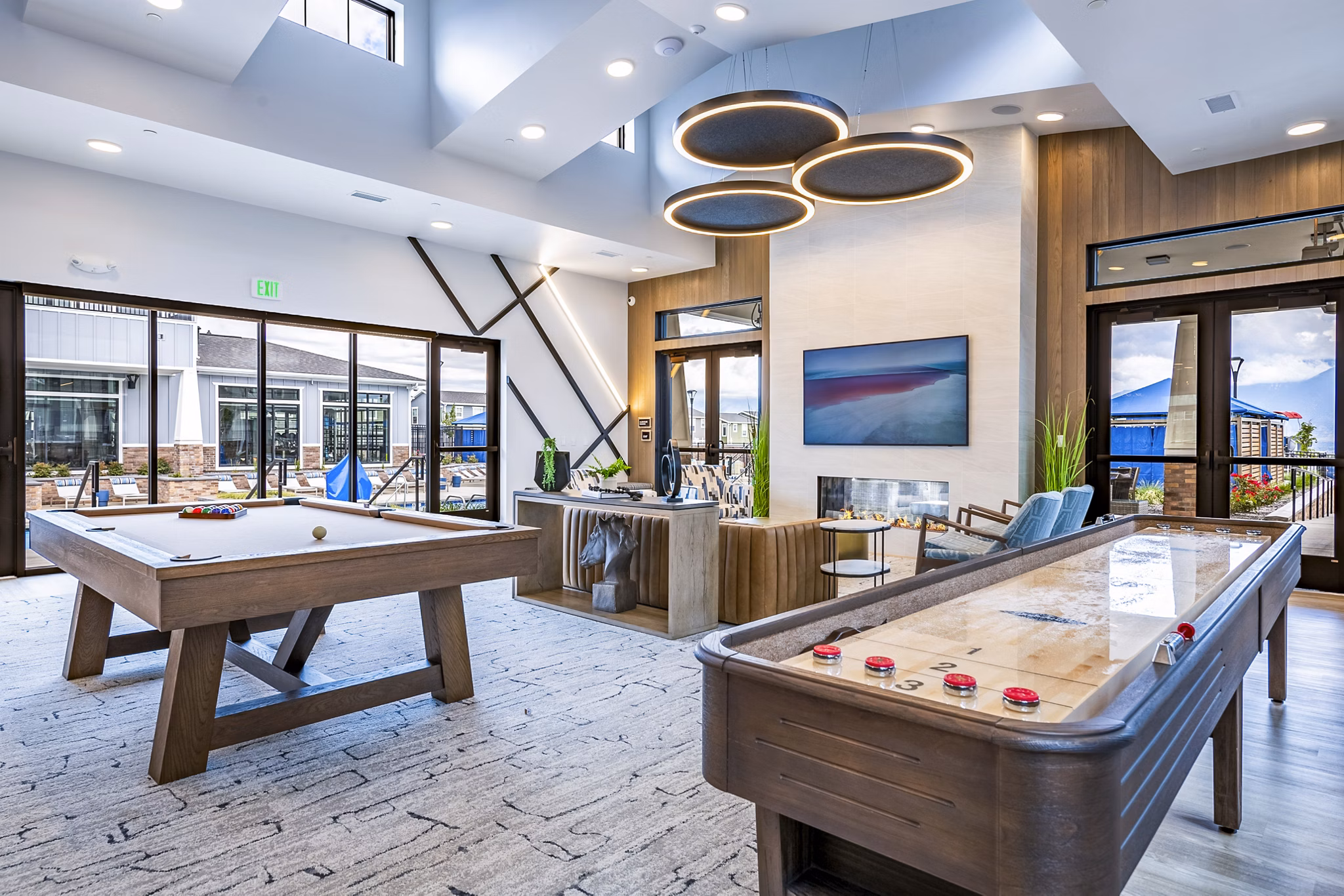 Clubhouse game room with pool table and lounge seating at Viviano at Riverton Apartments