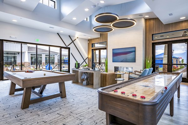 Clubhouse game room with pool table and lounge seating at Viviano at Riverton Apartments
