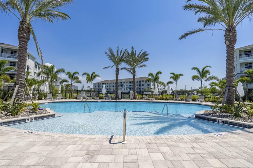 Inviting pool area with lounge chairs at The Palms at Cape Coral Apartments