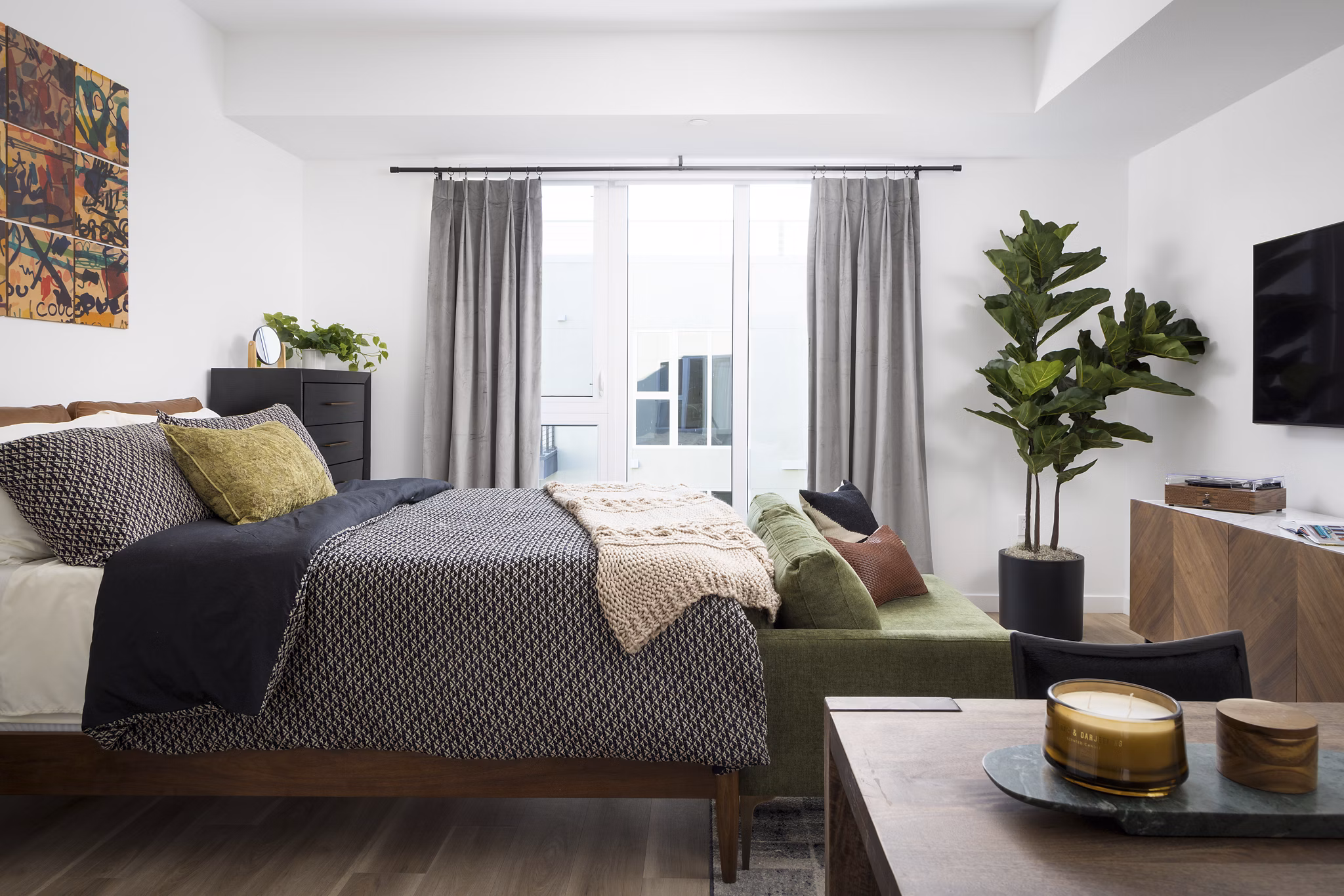 Cozy bedroom with modern decor at The Louise 4900 Apartments, featuring luxurious bedding and ample natural light