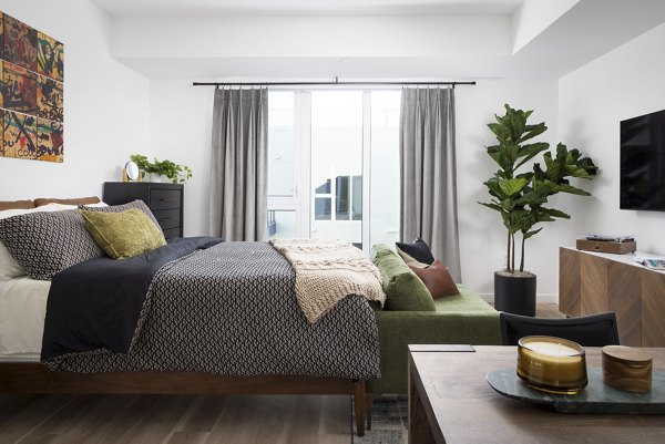 Cozy bedroom with modern decor at The Louise 4900 Apartments, featuring luxurious bedding and ample natural light