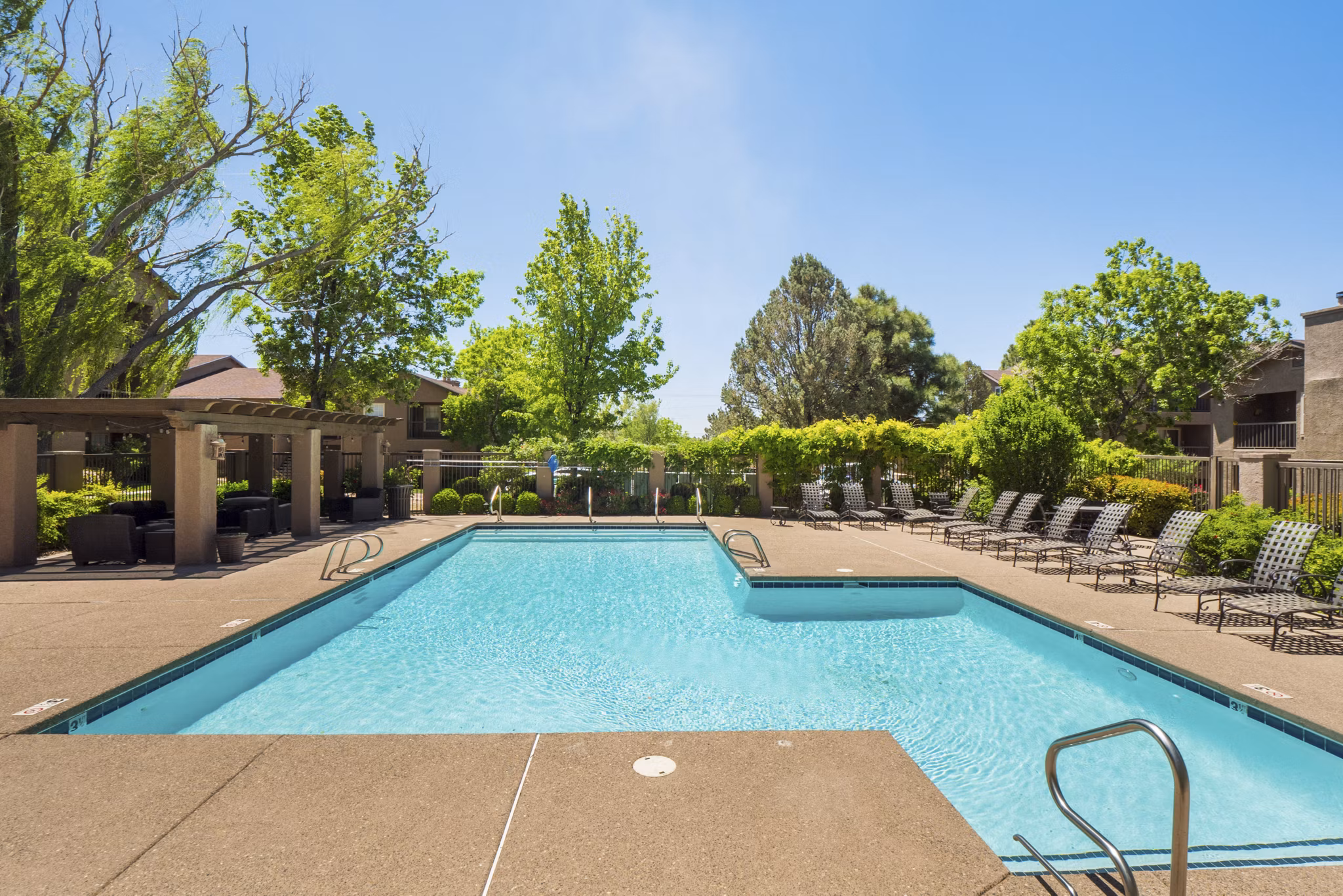 Outdoor swimming pool at Hunters Ridge Apartments with lounge chairs and surrounding greenery