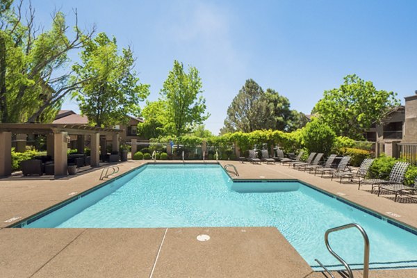 Outdoor swimming pool at Hunters Ridge Apartments with lounge chairs and surrounding greenery