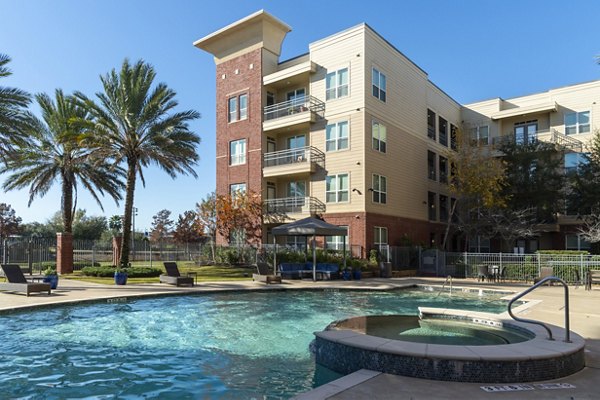 Pool deck at Regard at Med Center Apartments: Luxury swimming pool with sun loungers and lush landscaping in Houston, Texas