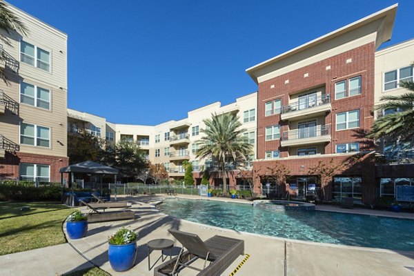 Luxurious pool area at Regard at Med Center Apartments featuring modern lounge chairs and lush landscaping