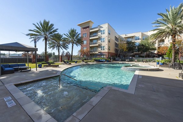 Luxurious pool area at Regard at Med Center Apartments, featuring elegant lounge chairs and lush landscaping