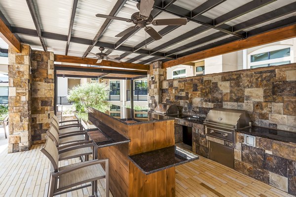 Outdoor patio with modern grill area at Tribute at the Rim Apartments, ideal for social gatherings and relaxation in a luxury setting