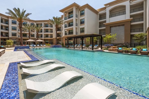 Resort-style pool with lounge chairs at Tribute at the Rim Apartments offering luxury living