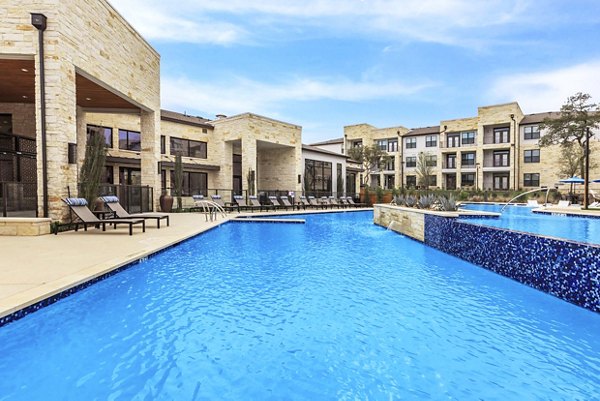 Pool with sun loungers at TruNorth at Bulverde Apartments