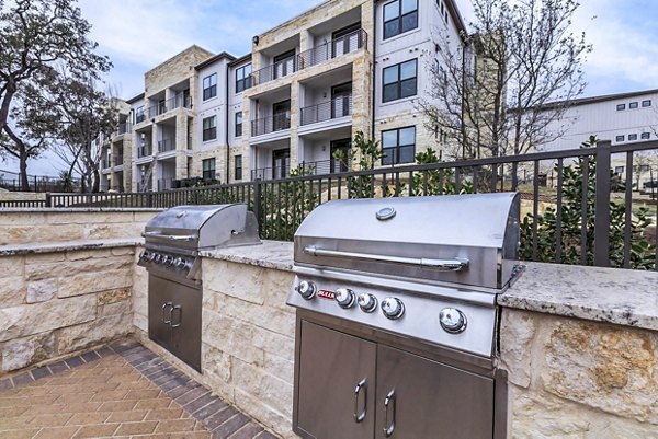 Modern outdoor grill area with seating at TruNorth at Bulverde Apartments