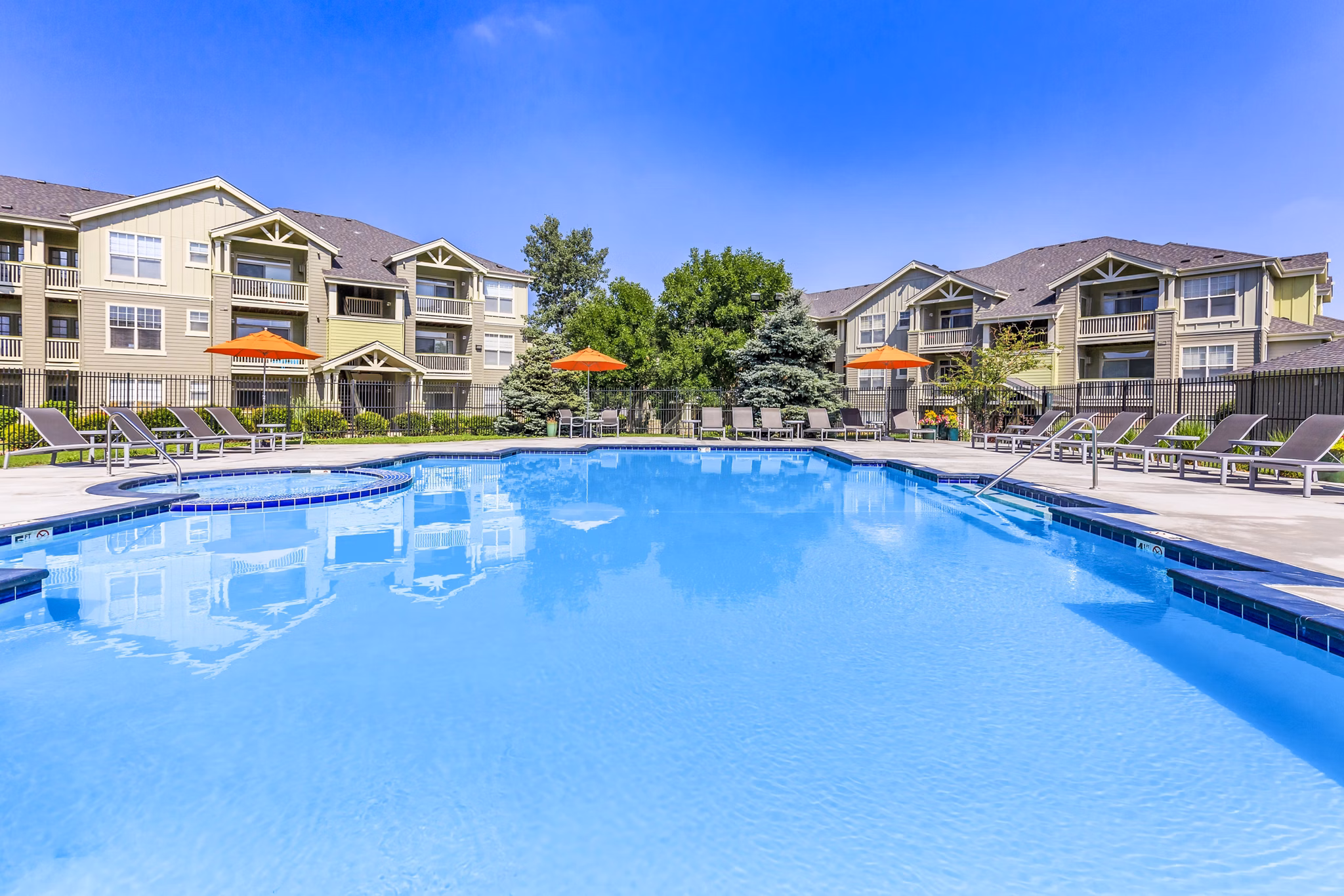 Outdoor swimming pool at Links at Legacy Ridge Apartments with loungers and parasols, an ideal spot for relaxation and recreation