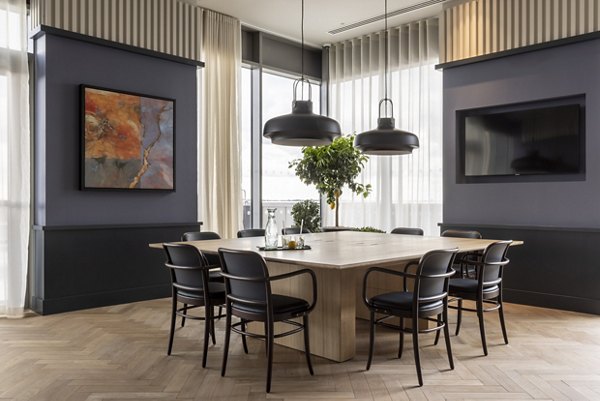 Dining area with a round table and chic black chairs, featuring modern decor and lighting at Lyons Dock.