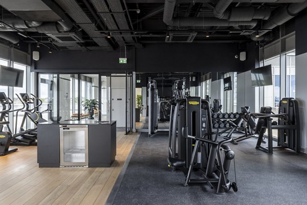 Fully equipped fitness center at Lyons Dock with a variety of gym equipment and large windows for natural light.