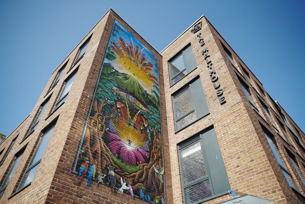Exterior view of Canvas Bristol with striking architecture and a colorful mural decorating the building facade.