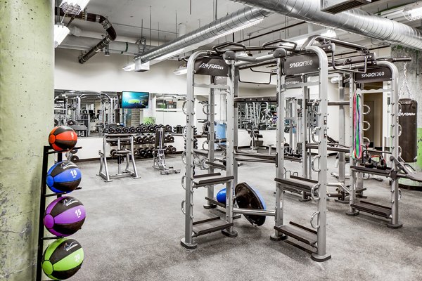 Modern fitness center with state-of-the-art equipment at Hecht Warehouse Apartments, featuring spacious workout areas