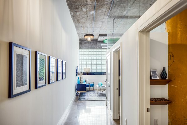 Bright hallway with exposed brick walls and industrial lighting at Hecht Warehouse Apartments