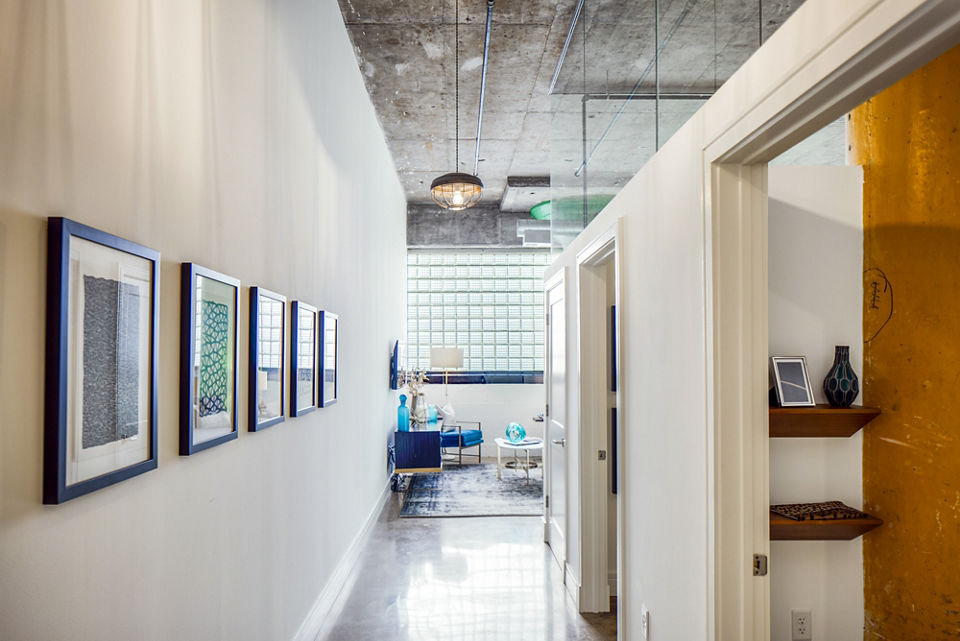 Bright hallway with exposed brick walls and industrial lighting at Hecht Warehouse Apartments