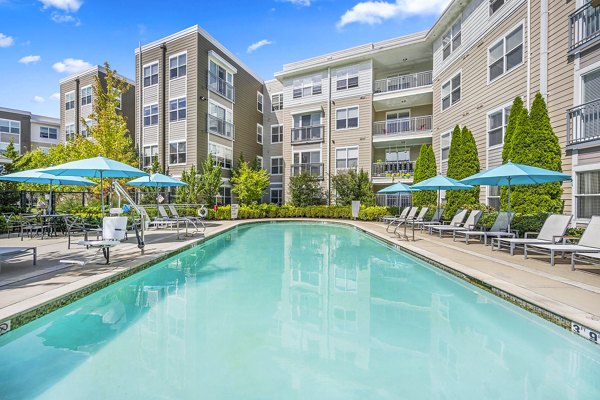 Resort-style pool at The Landing at Vinnin Square Apartments with lounge chairs and lush landscaping for luxury relaxation