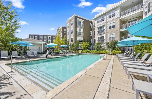 Community pool at The Landing at Vinnin Square Apartments featuring lounge chairs and sunshade structures