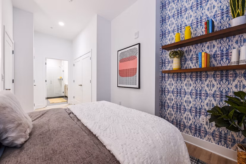 Bedroom featuring modern decor and large windows at SoNYa Apartments, offering a cozy and inviting living space in a luxury setting