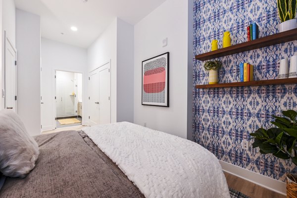 Bedroom featuring modern decor and large windows at SoNYa Apartments, offering a cozy and inviting living space in a luxury setting