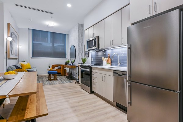 Modern kitchen featuring stainless steel appliances and sleek countertops in SoNYa Apartments