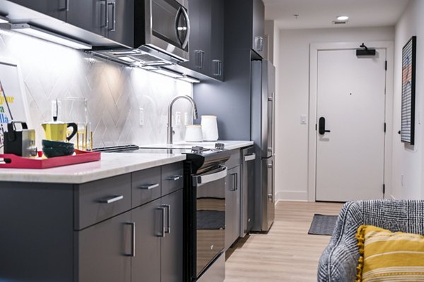 Modern kitchen with stainless steel appliances and island seating in SoNYa Apartments