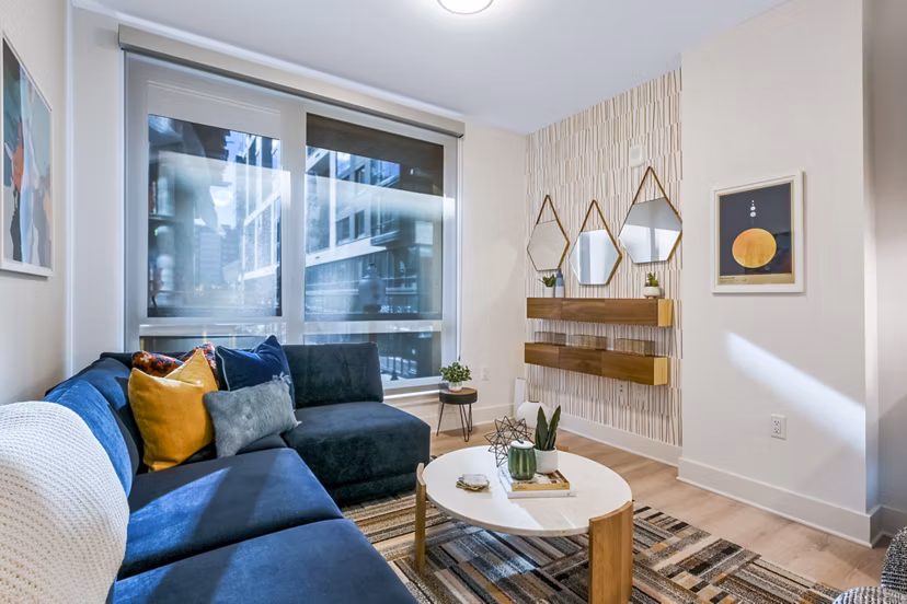 Spacious living room with modern decor and large windows at SoNYa Apartments, luxury residences by Greystar