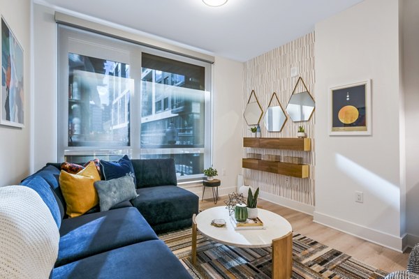 Spacious living room with modern decor and large windows at SoNYa Apartments, luxury residences by Greystar