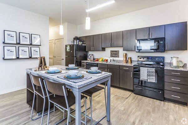 Modern kitchen with granite countertops and stainless steel appliances in The Edge Apartments