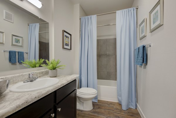 Bathroom with sleek fixtures and modern lighting at Roots at O'Connor Apartments