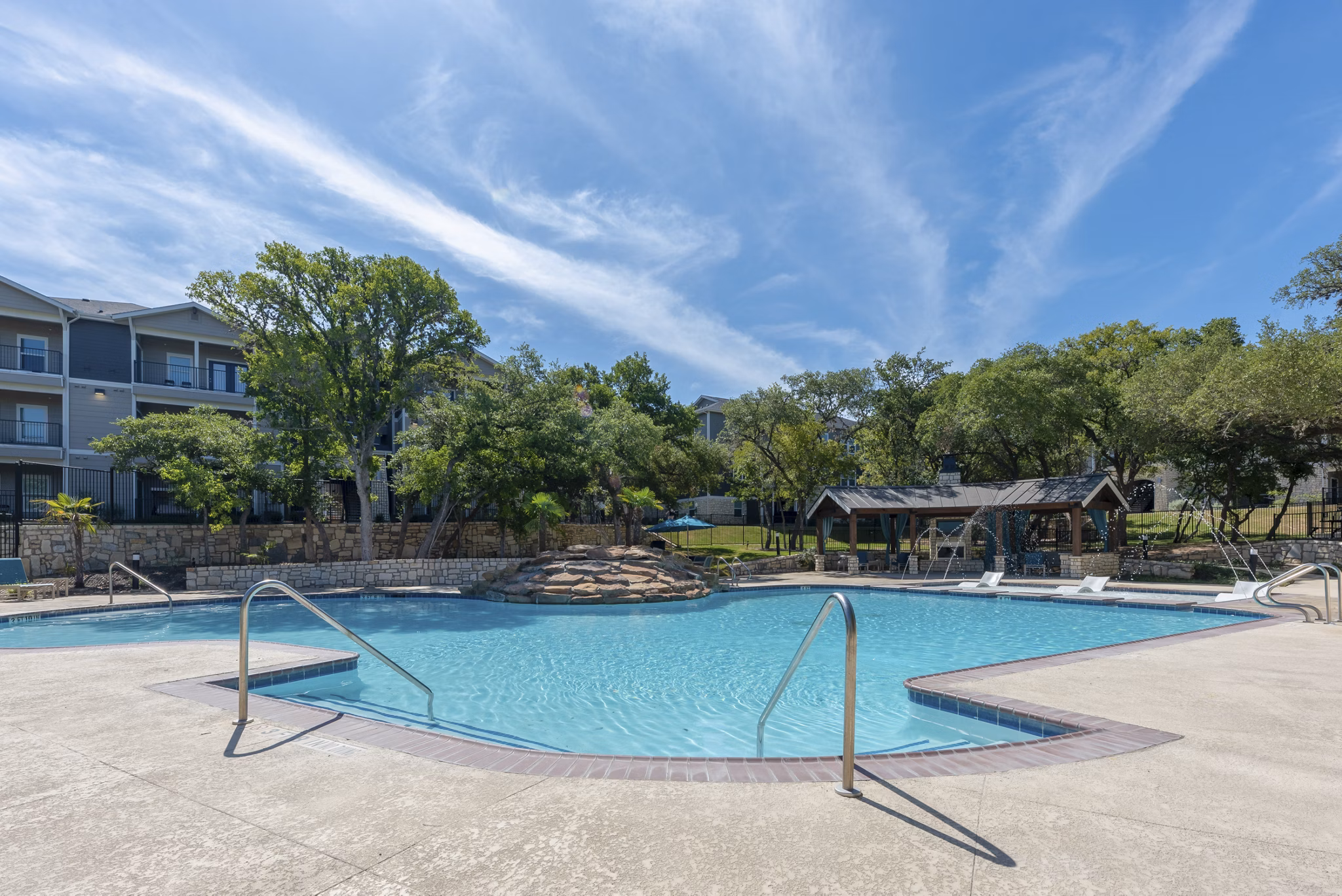 Pool surrounded by lush greenery at Roots at O'Connor Apartments