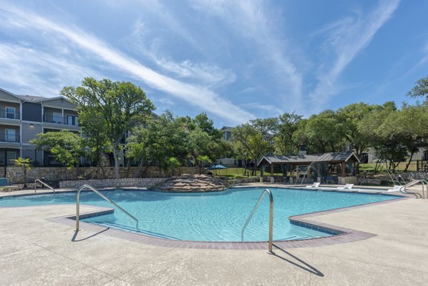 Pool surrounded by lush greenery at Roots at O'Connor Apartments